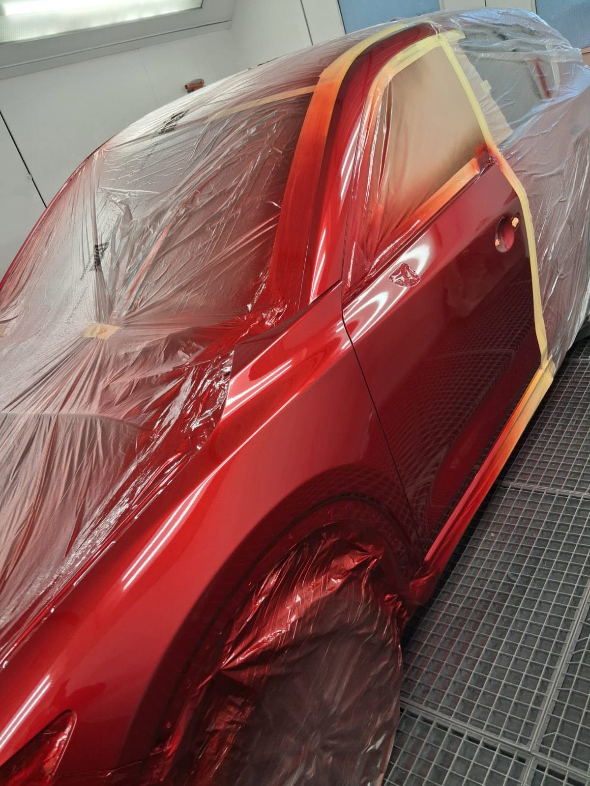 Red car refinishing in the spray booth