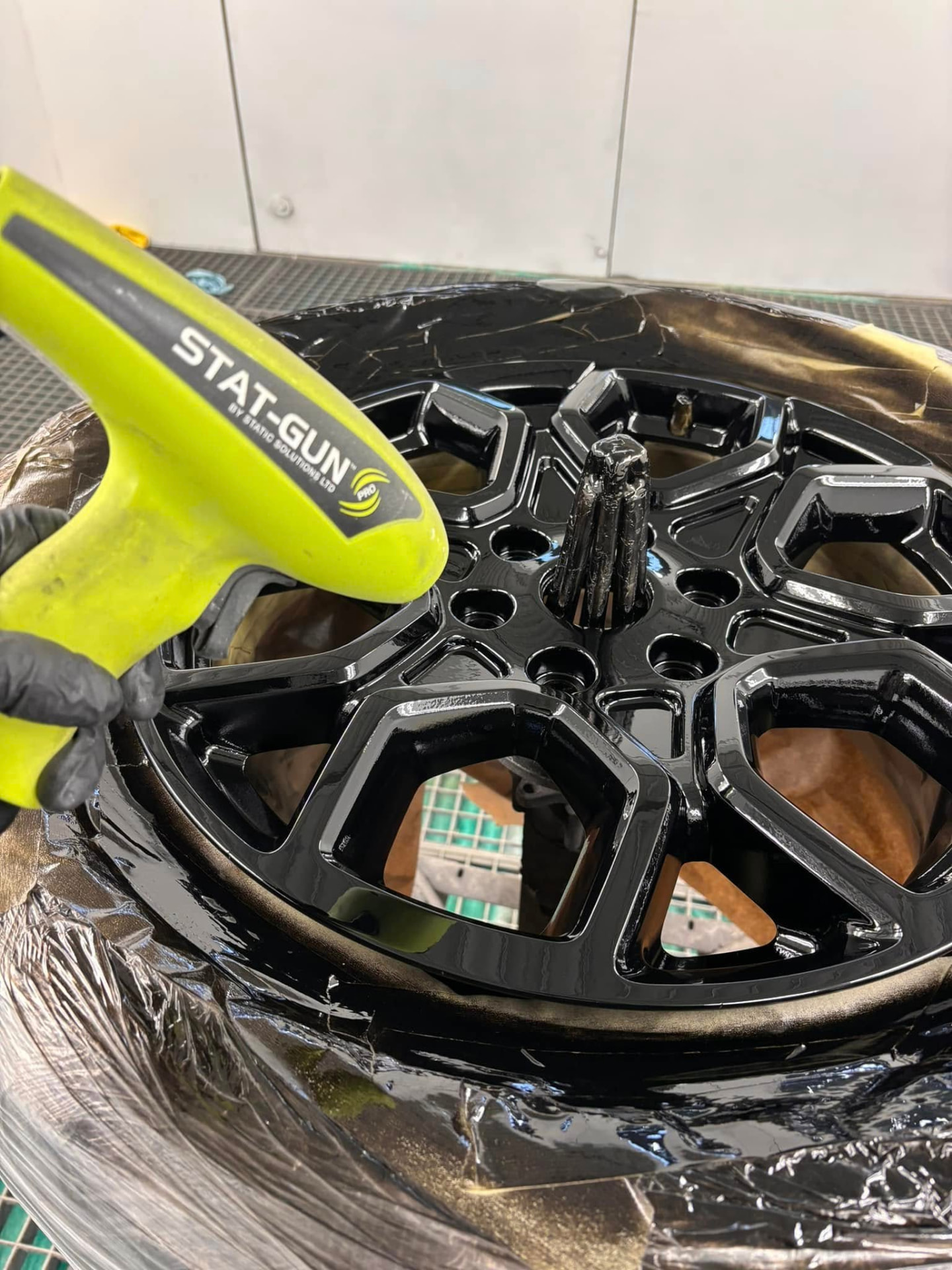 Gloss black alloy wheel being finished at Mayfs